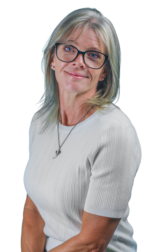 Portrait of a smiling woman with gray-blonde hair and black glasses, wearing a light gray ribbed top and a necklace.