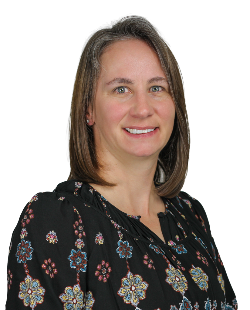 Close-up portrait of a smiling woman with shoulder-length brown hair wearing a black floral blouse.