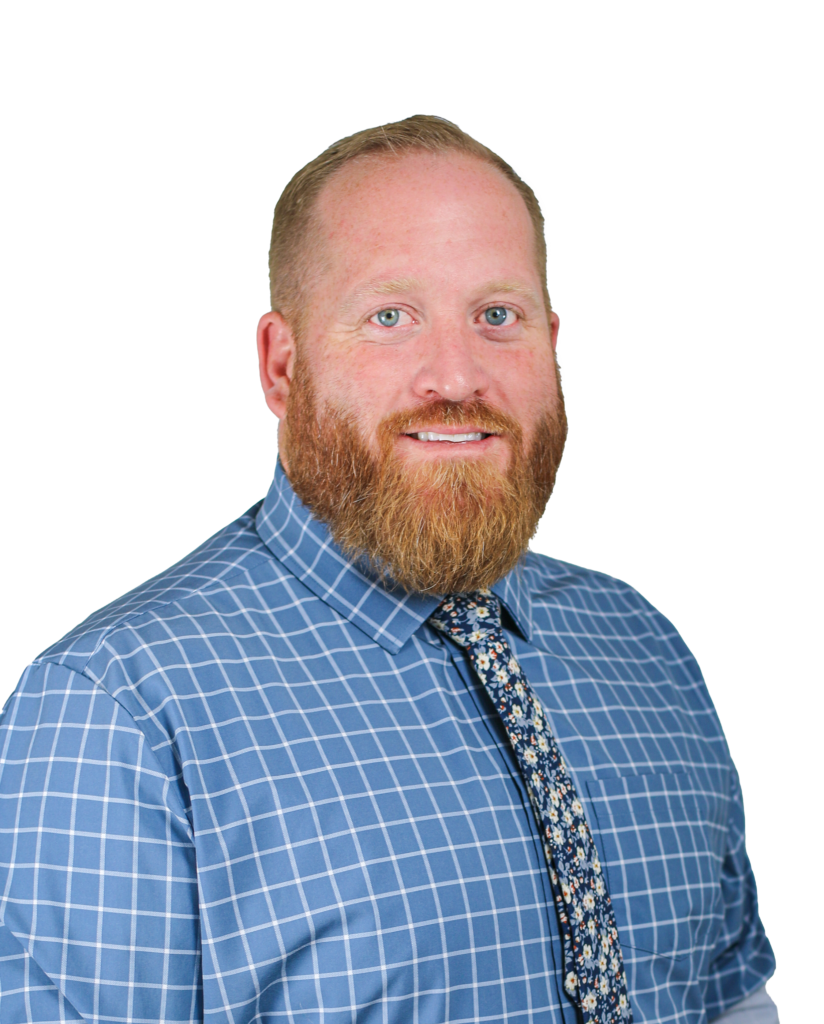 Portrait of a smiling man with a red beard, wearing a blue checkered shirt and a floral tie against a black background.