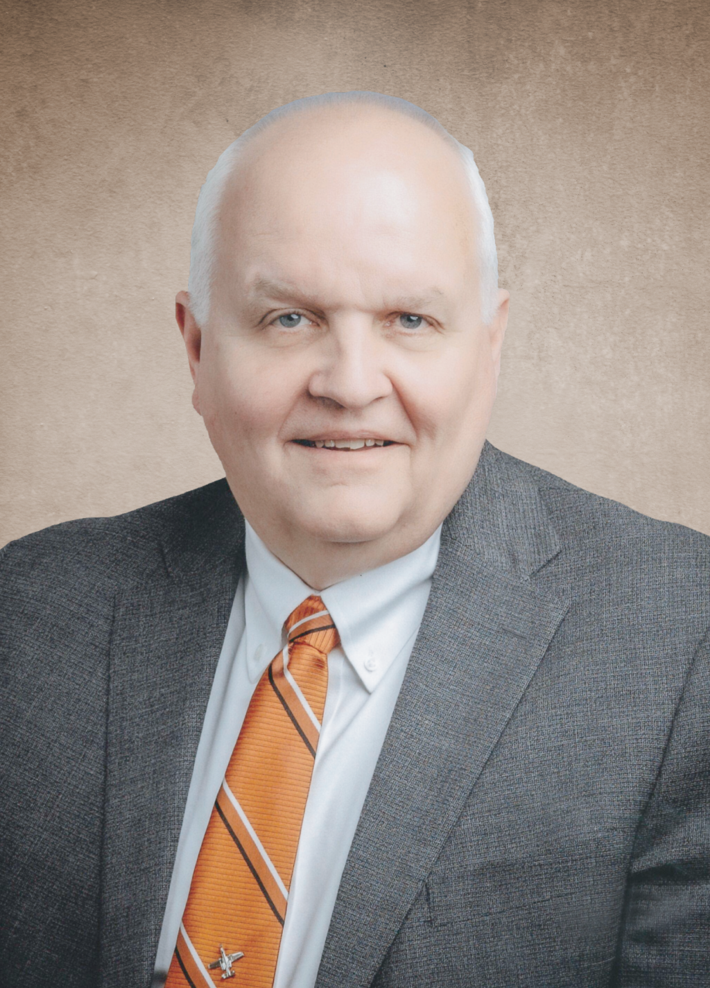 Portrait of an older man in a gray suit and orange striped tie, smiling, against a brown textured background, cropped at the chest up.
